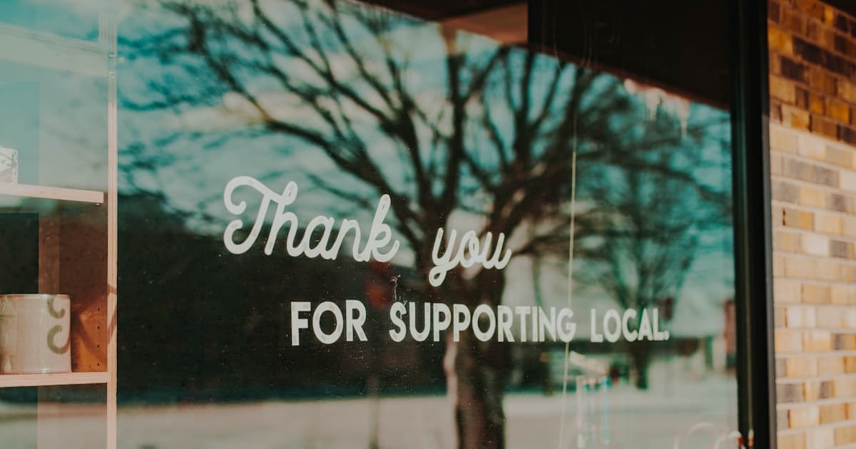 "Thank you for supporting local" sign displayed in a storefront window