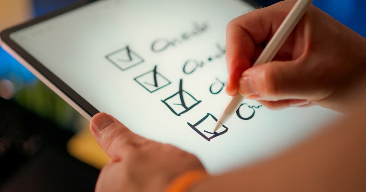 A hand checking off items on a digital checklist on a tablet