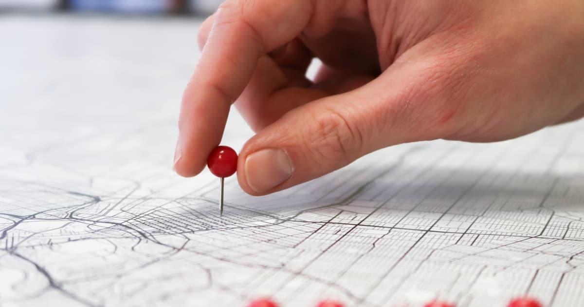 A person placing a red pin on a city map